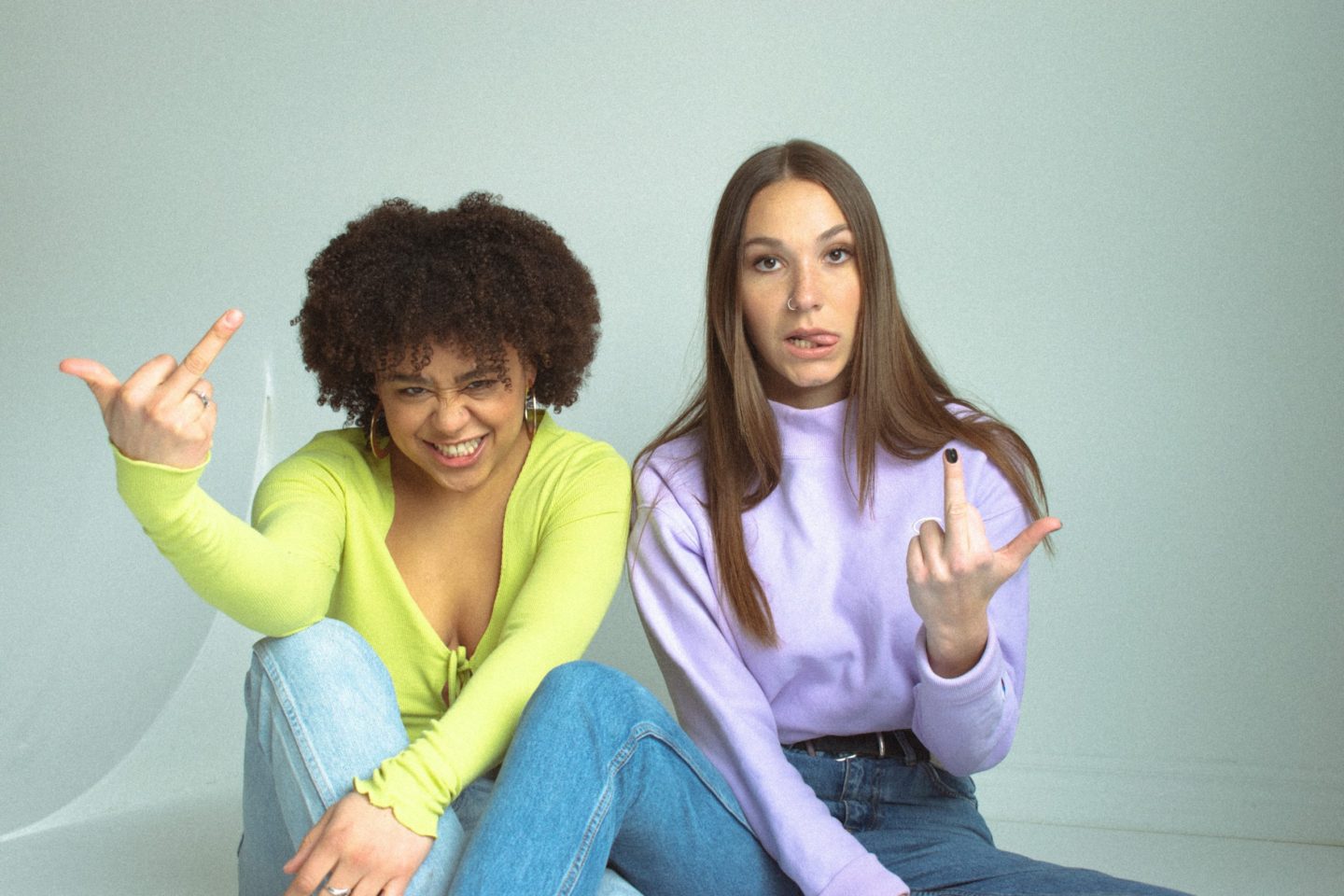 Black female sitting next to white female swearing at the camera
