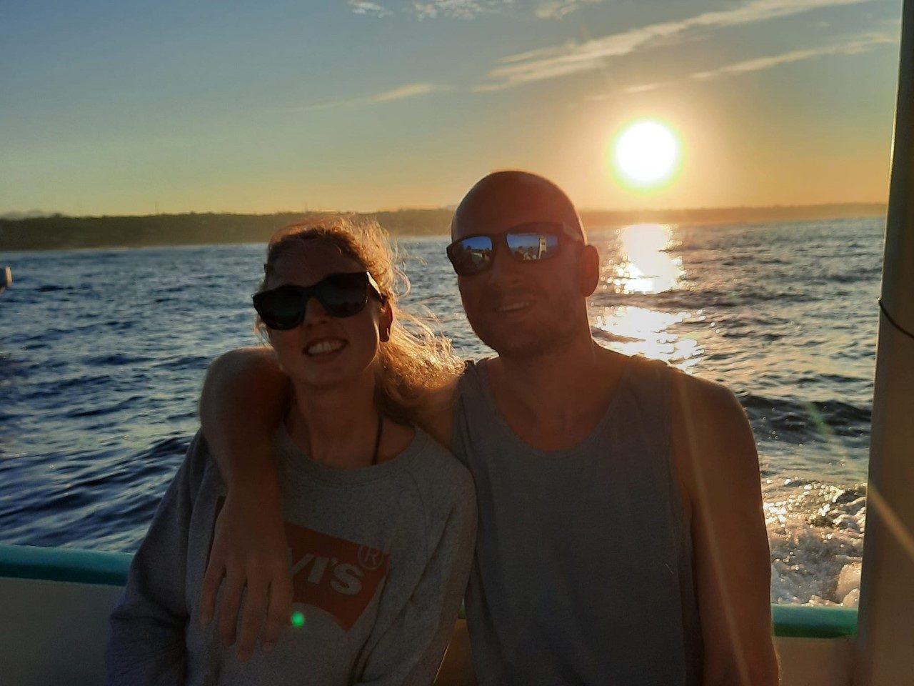couple sat on a boat with the sun rising behind them