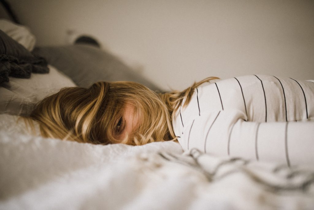 woman laying on bed with her hair falling over her face and one eye open