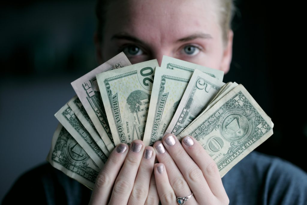 woman holding up money in front of her face