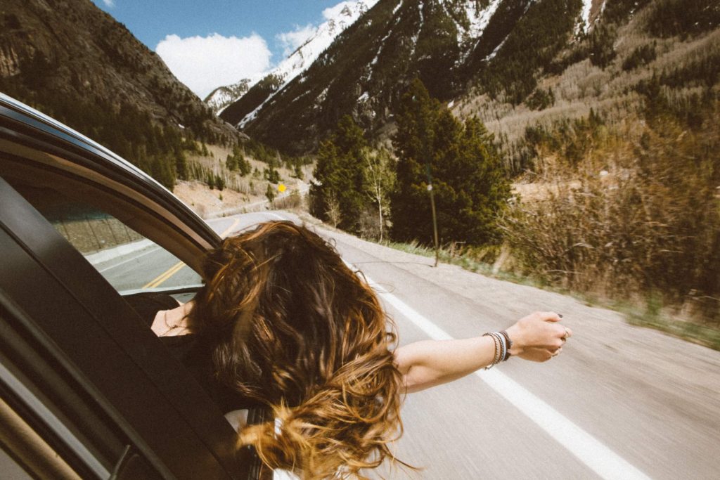 woman sticking her head out the car window enjoying her freedom