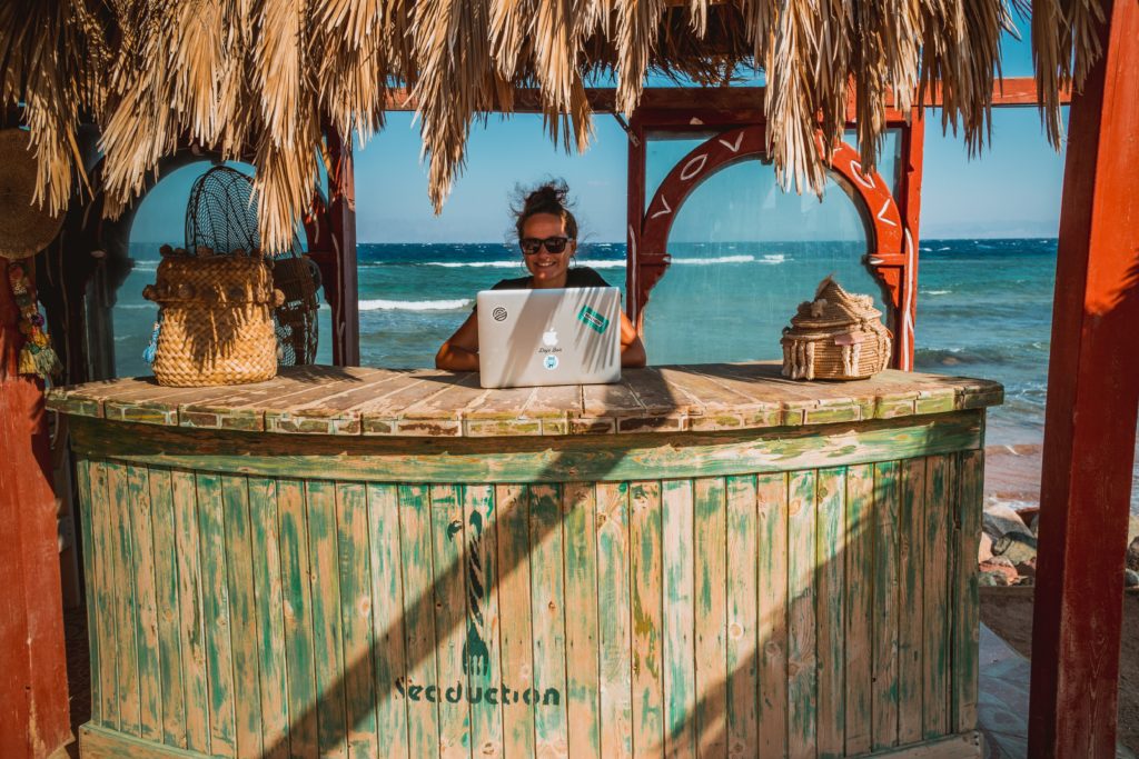 Female digital nomad working remotely at the beach