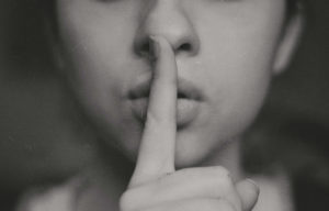 Woman with finger over her mouth in a shh position