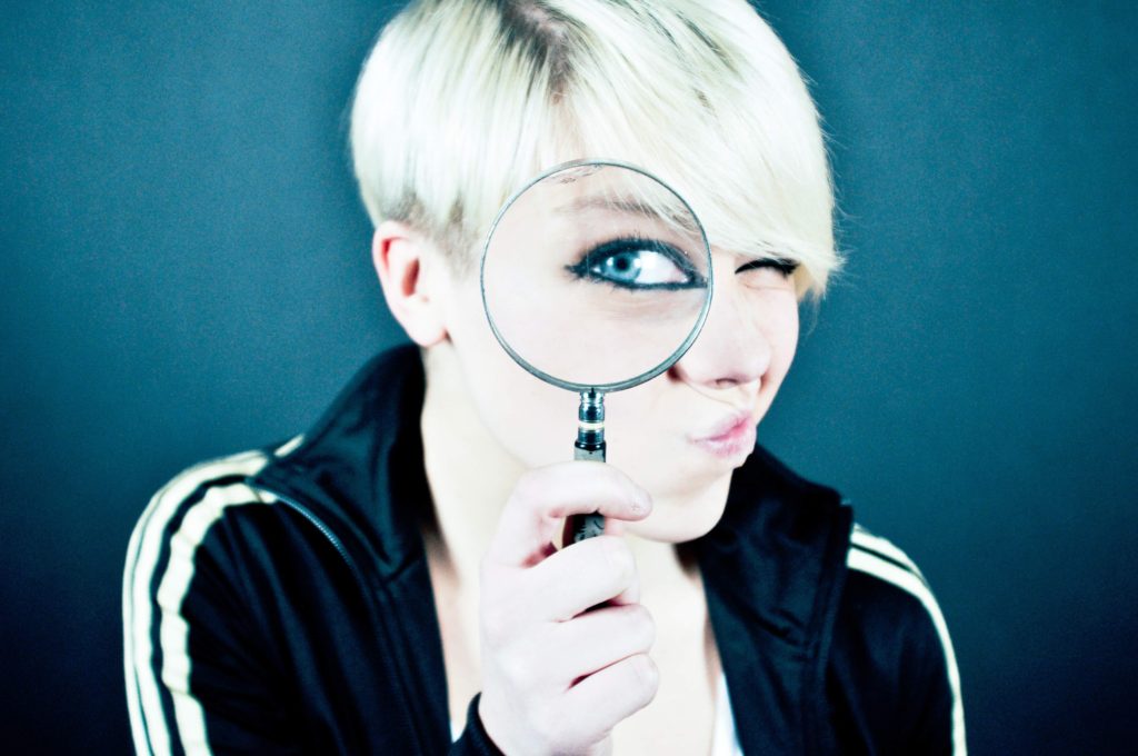 Woman holding magnifying glass up to her eye