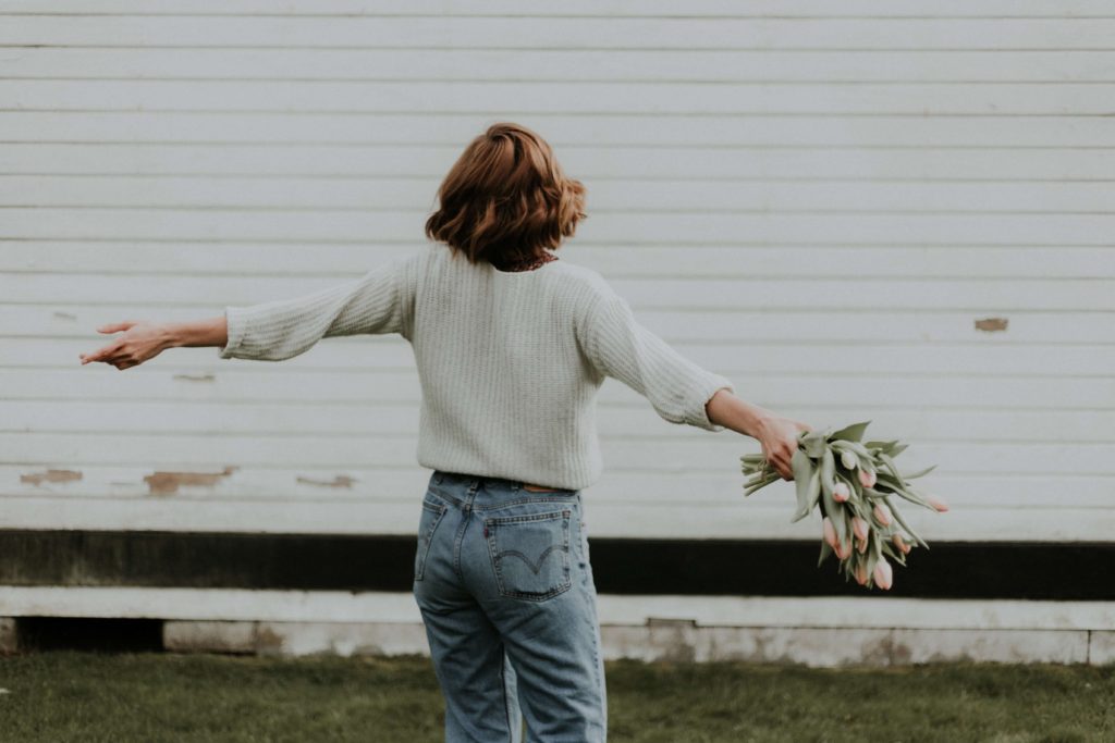 Woman holding flowers with arms open