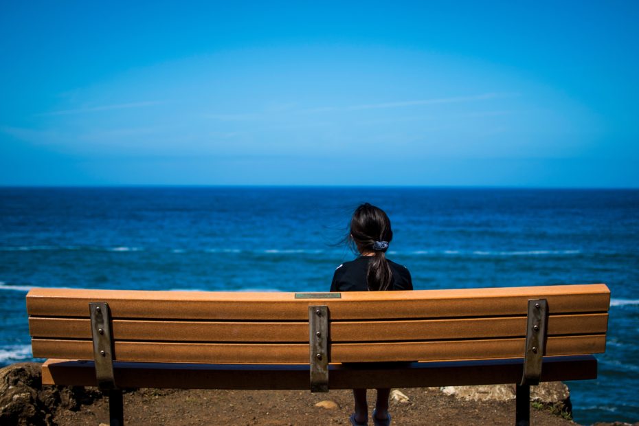 Woman sat on a bench looking at the sea
