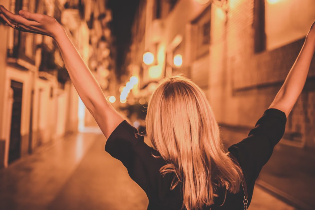 Woman walking the streets with her arms lifted in joy