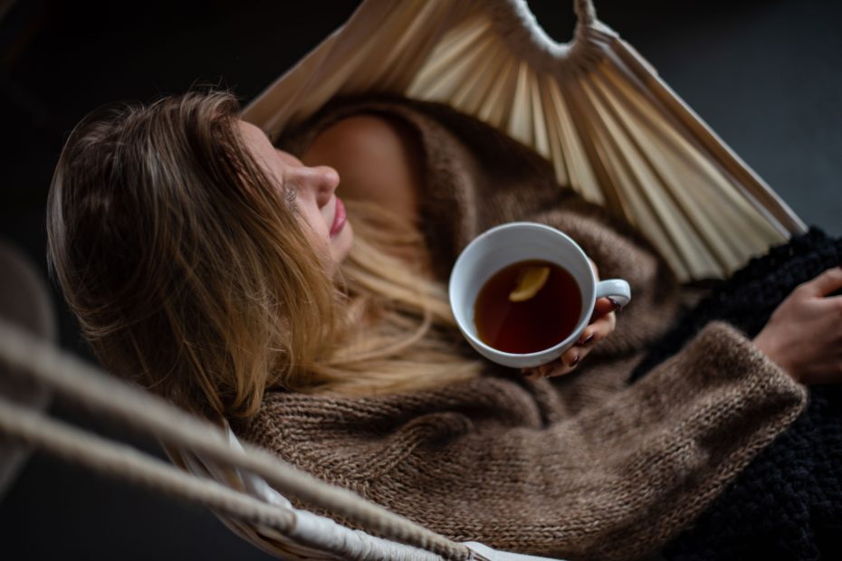 Woman sitting in a hammock drinking hot tea