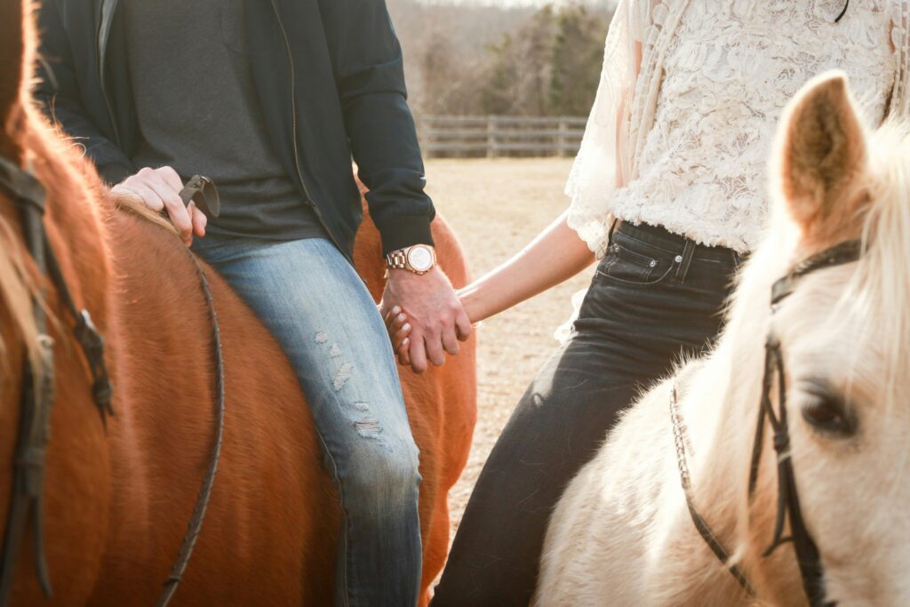 Two people horse-riding and holding hands on a first date