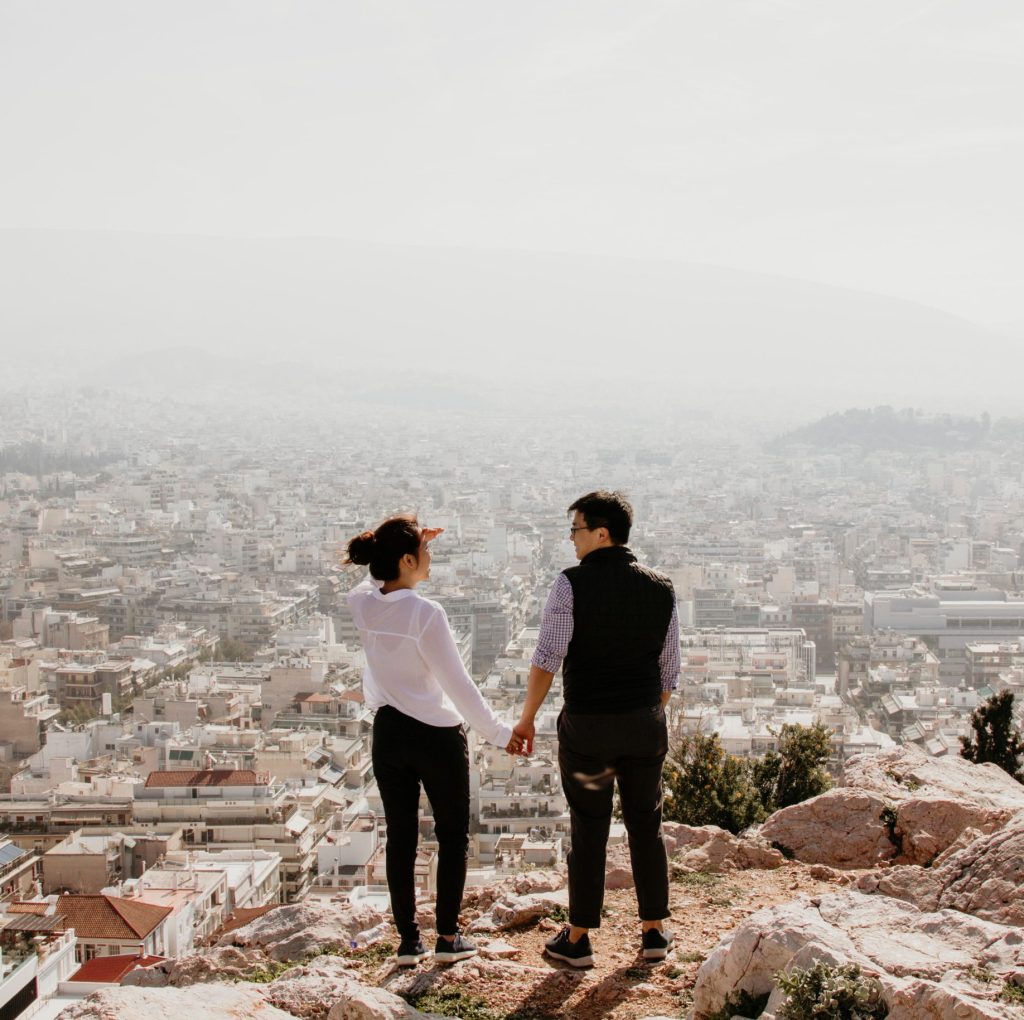 couple holding hands looking out to a city